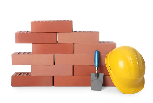 Many red bricks, hard hat and trowel on white background