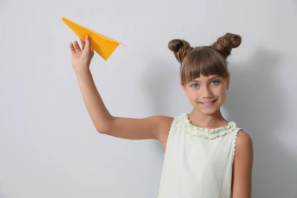 Милая Маленькая Девочка Играет Бумажной Плоскостью Светло Сером Фоне — стоковое фото