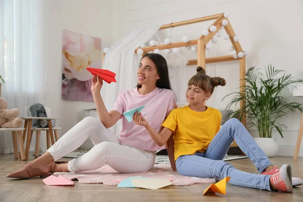 快乐的母亲和女儿在房间的地板上玩纸飞机 — 图库照片