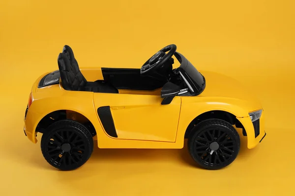 Sarı Arka Planda Çocuğun Elektrikli Oyuncak Arabası — Stok fotoğraf