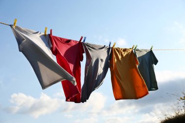 Elbiseler gökyüzüne karşı çamaşır ipine asılı.