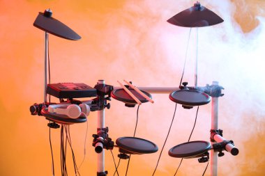 Modern elektronik davul seti ve turuncu arka planda duman. Müzik aleti