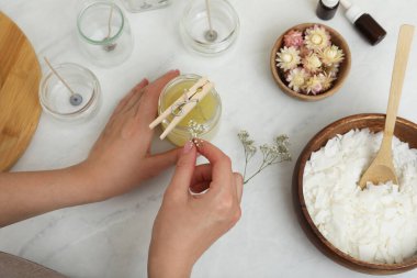 Masada ev yapımı mumları çingene çiçekleriyle süsleyen kadın.