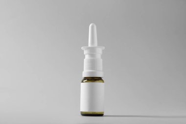 Gri arka planda bir şişe burun spreyi.