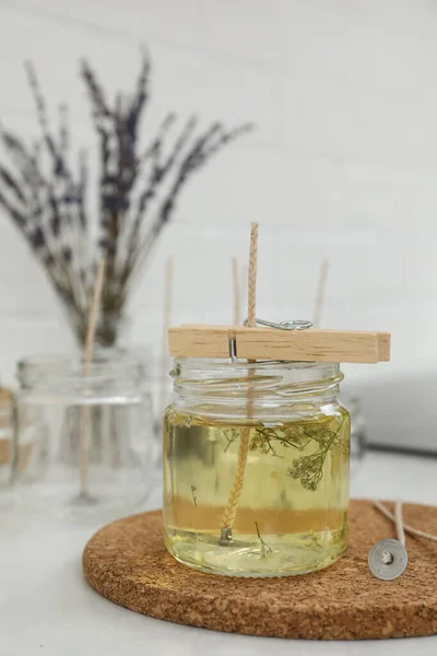 Glass jar with melted wax on white table. Handmade candle