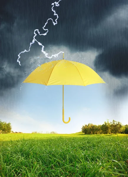 緑の牧草地で大雨の下で黄色の傘を開く — ストック写真
