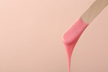 Bej arka planda sıcak tüy dökücü cila ile ahşap spatula. Metin için boşluk