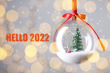 Metin Merhaba 2022 ve güzel şeffaf Noel süsü bulanık festival ışıklarına karşı, bokeh etkisi
