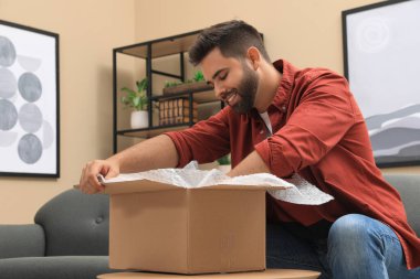 Evdeki paketleri açan adam. İnternetten alışveriş