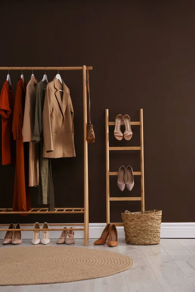 Modern dressing room interior with clothing rack near brown wall