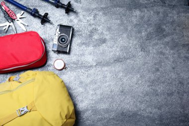 Turist sırt çantası ve gri arka planda diğer farklı kamp ekipmanları ile düz kompozisyon, metin için boşluk