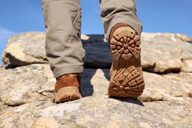 Uçuruma tırmanan bir turist, bacaklara yakın.