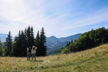 Kadınlar güneşli bir günde, dağ manzarasının tadını çıkarıyorlar. Metin için boşluk