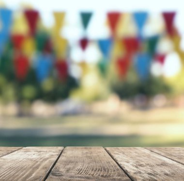 Parktaki boş ahşap masa kiraz bayraklarıyla süslenmiş, tasarım için yer var. Açık hava partisi.