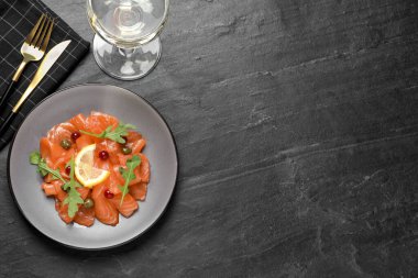 Siyah masada servis edilen kapari, kızılcık, roka ve limonlu somon carpaccio. Metin için boşluk