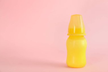 Pembe arka planda bebek mamasıyla beslenme şişesi, mesaj için boşluk. Bebek sütü