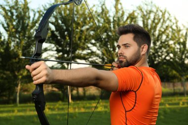 Ok ve yaylı adam parkta okçuluk yapıyor.