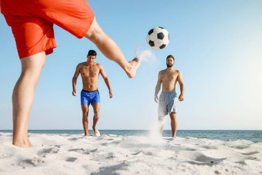 Sahilde futbol oynayan bir grup arkadaş.