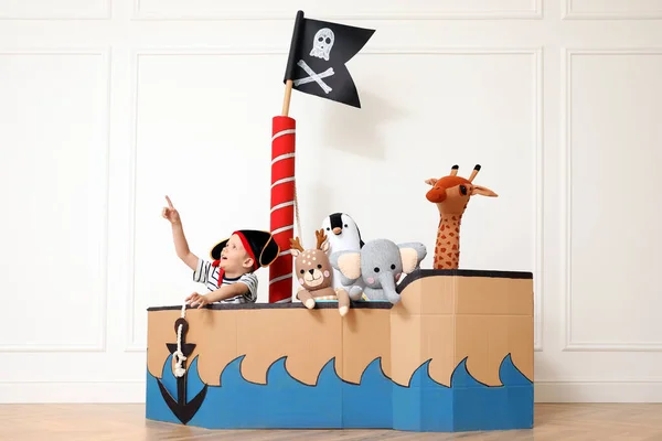 Niedlicher Kleiner Junge Spielt Mit Spielzeug Piratenpappschiff Nahe Weißer Wand — Stockfoto