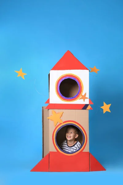 Açık Mavi Arka Planda Karton Roketle Oynayan Sevimli Küçük Çocuk — Stok fotoğraf