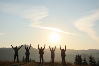 Dağlarda güneşin doğuşunu izleyen bir grup insan. Metin için boşluk