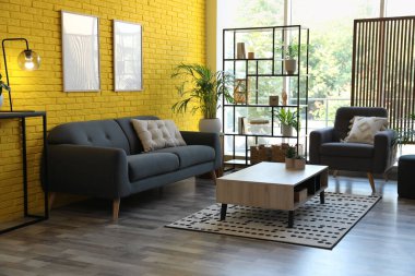 Rahat gri bir kanepe ve odada bir koltuk. İç tasarım