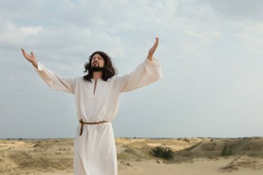 Yüce İsa, güneşli bir günde çölde el kaldırıyor.