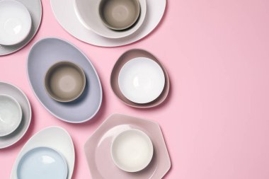 Pembe arka planda farklı tabak ve kaseler, düz yatış. Metin için boşluk