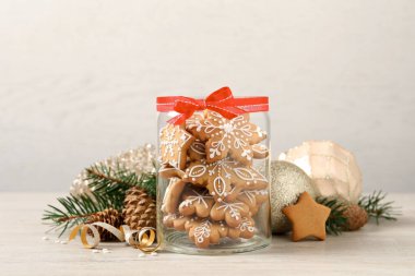 Cam kavanozda lezzetli Noel kurabiyeleri ve bej ahşap masada şenlikli bir dekor.