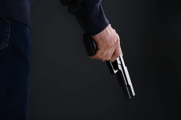 Man holding gun on black background, closeup