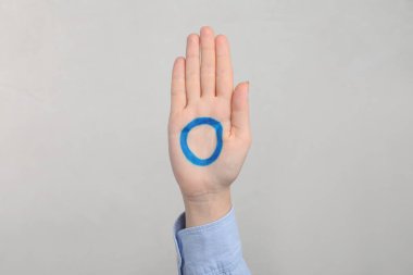 Avuç içine çizilmiş mavi halkalı bir kadın açık gri arka planda, yakın plan. Dünya Diyabet Günü