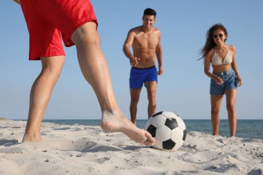 Sahilde futbol oynayan bir grup arkadaş.