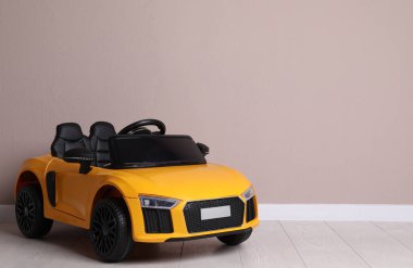 Bej duvarın yanındaki çocuk elektrikli oyuncak arabası. Metin için boşluk