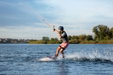 Genç çocuk nehirde wakeboard yapıyor. Aşırı su sporu