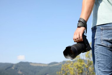 Dağlardaki modern kameralı profesyonel fotoğrafçı, yakın plan. Metin için boşluk