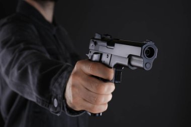 Siyah arka planda silah tutan adam, yakın plan.