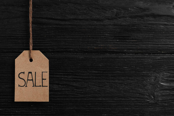 Sale tag on wooden background, space for text. Black Friday concept
