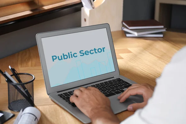 Public Sector. Man working with modern laptop at wooden table, closeup