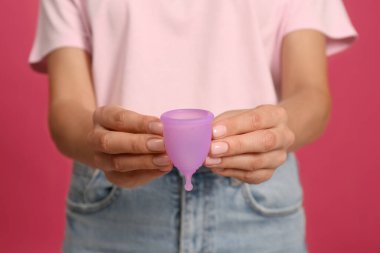 Aybaşı fincanı parlak pembe arkaplanlı genç kadın, yakın plan.