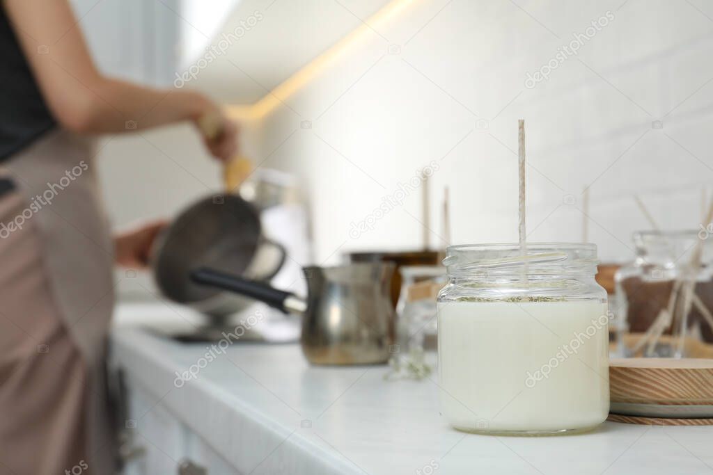 Homemade candle and blurred view of woman on background