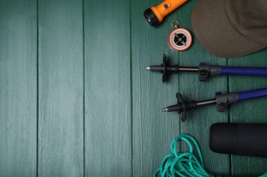 Yeşil ahşap zemin üzerinde yürüyüş direkleri ve diğer yürüyüş ekipmanları ile düz bileşim, metin için alan