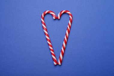Mavi arka planda tatlı Noel şekerlerinden yapılmış kalp şekli, üst manzara.