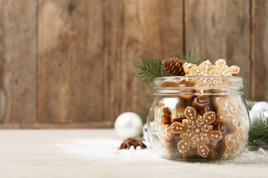 Cam kavanozda lezzetli Noel kurabiyeleri ve bej ahşap masada şenlikli bir dekor. Metin için boşluk