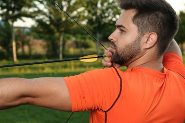 Ok ve yaylı adam parkta okçuluk yapıyor.