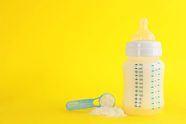 Bebek mamasıyla beslenme şişesi ve sarı arka planda toz kepçesi, mesaj için boşluk. Bebek sütü