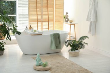 Modern küvet ve güzel bitkilerle dolu şık bir banyo.
