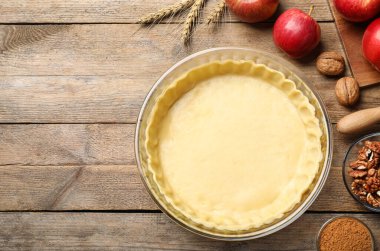 Düz kompozisyon, ham hamur ve malzeme ile ahşap masa üzerinde, metin için boşluk. Elmalı turta yapıyorum.