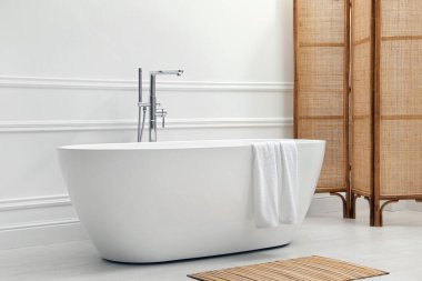 Modern seramik küvet ve beyaz duvarın yanındaki katlanan ekran.