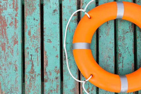 stock image Orange life buoy on turquoise wooden background, top view. Space for text