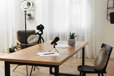 Odadaki masanın yakınındaki tripodlarda kamera ve ışıklandırma ekipmanları var. Blogger işyeri